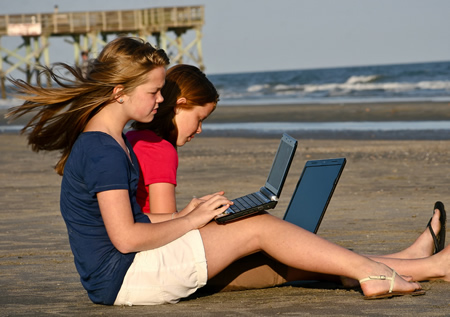 Teens Work on Laptops at the Beach