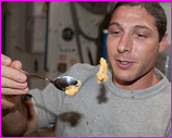 NASA astronaut Michael Hopkins, Expedition 37 flight engineer, uses a spoon to eat in space